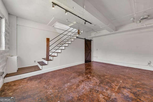 unfurnished living room with concrete floors, baseboards, a barn door, and stairs