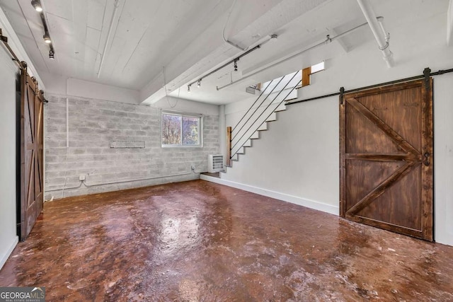 basement with track lighting, stairway, and a barn door