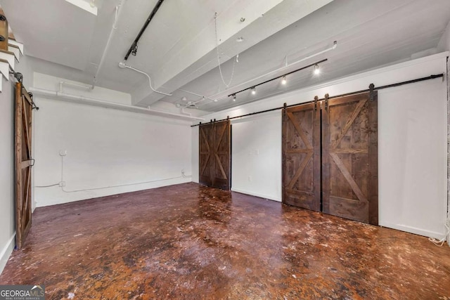 basement with baseboards and a barn door