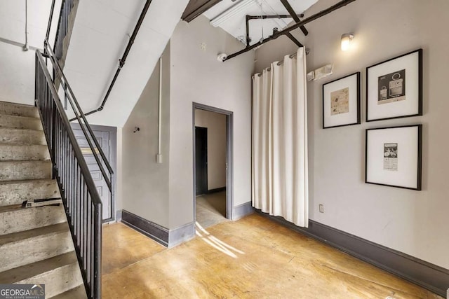 staircase with a high ceiling, concrete flooring, and baseboards
