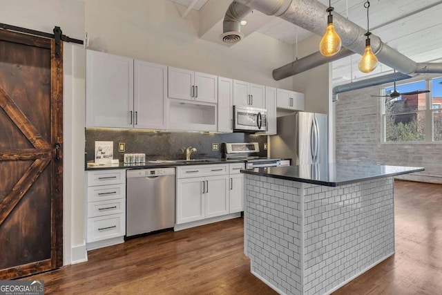 kitchen with stainless steel appliances, dark wood-style flooring, decorative backsplash, and dark countertops