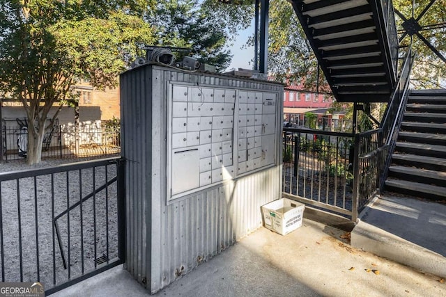 view of home's community featuring mail area, fence, and stairs