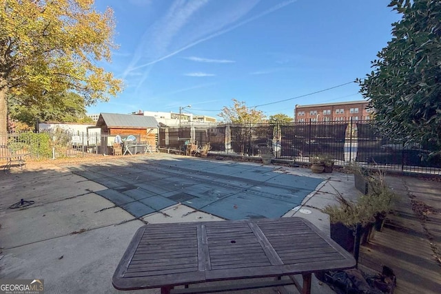view of swimming pool featuring an outdoor structure, fence, a fenced in pool, and a patio
