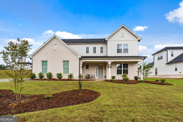 view of front of house with a porch, board and batten siding, a front lawn, and brick siding
