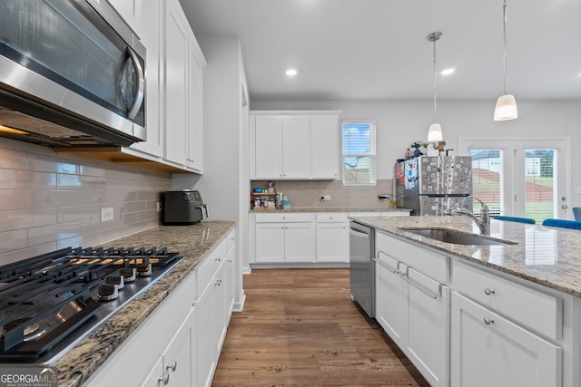 kitchen with white cabinetry, a wealth of natural light, appliances with stainless steel finishes, and wood finished floors
