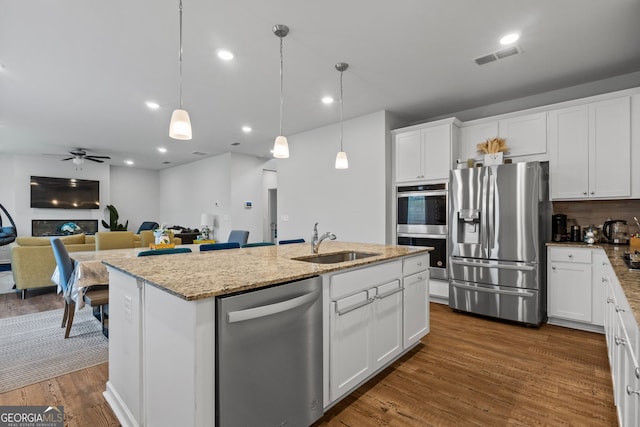 kitchen featuring an island with sink, dark wood-type flooring, white cabinets, appliances with stainless steel finishes, and a sink