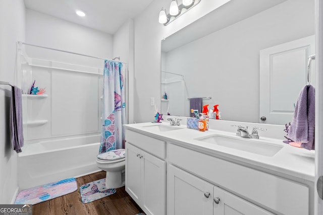 bathroom with toilet, wood finished floors, double vanity, and a sink