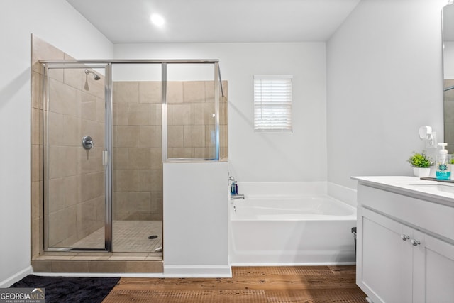bathroom with vanity, a stall shower, wood finished floors, and a garden tub
