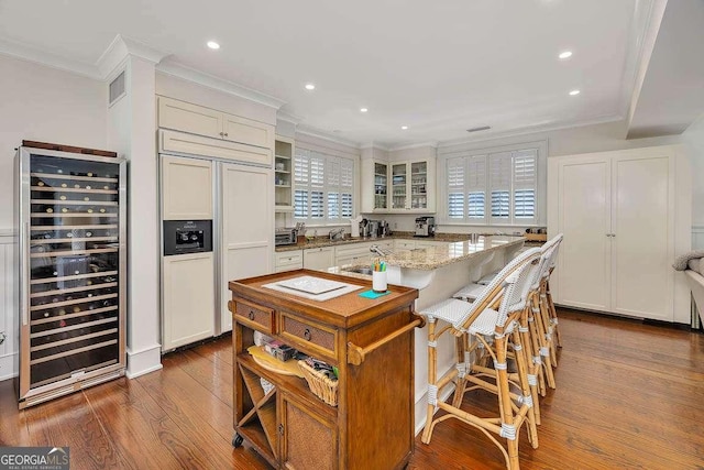 17 Sea Oats Ln, Saint Simons, GA 31522 - kitchen with glass insert cabinets, dark wood finished floors, crown molding, paneled fridge, and beverage cooler