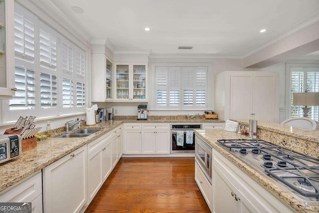 17 Sea Oats Ln, Saint Simons, GA 31522 - kitchen featuring crown molding, white cabinets, appliances with stainless steel finishes, a sink, and wood finished floors