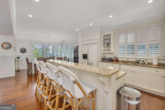 17 Sea Oats Ln, Saint Simons, GA 31522 - kitchen featuring a center island, a sink, paneled built in refrigerator, a wainscoted wall, and light stone counters