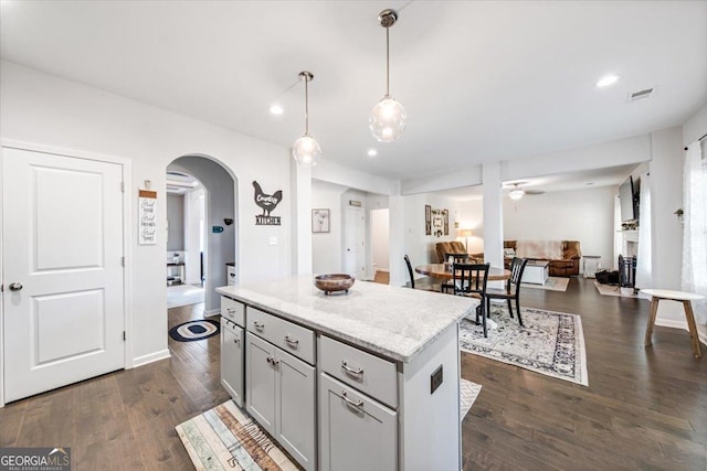5321 Felles Way, Forsyth, GA 31029 - kitchen with arched walkways, ceiling fan, a kitchen island, open floor plan, and dark wood-style floors