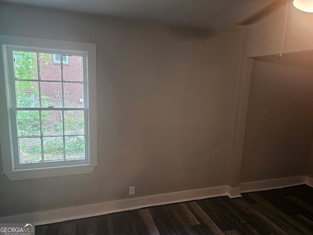 unfurnished room featuring a healthy amount of sunlight, baseboards, and dark wood-style floors
