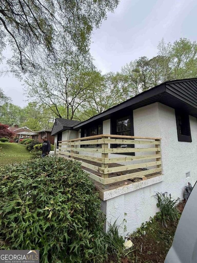 view of side of property with stucco siding and a balcony