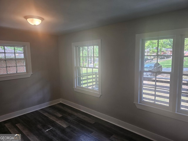 spare room with baseboards and dark wood-style floors