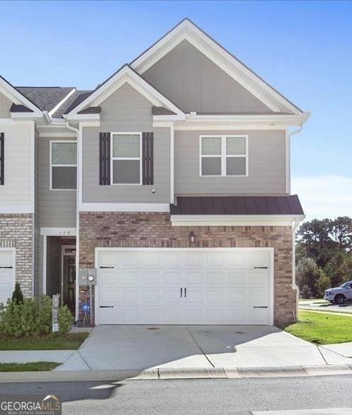 view of front of home with board and batten siding, an attached garage, brick siding, and driveway