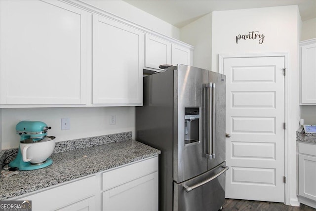 kitchen featuring light stone counters, stainless steel fridge, dark wood-style floors, and white cabinets