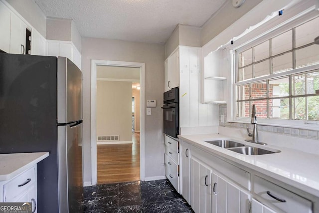 kitchen featuring visible vents, oven, a sink, freestanding refrigerator, and marble finish floor