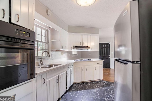 kitchen featuring light countertops, freestanding refrigerator, oven, a sink, and stovetop