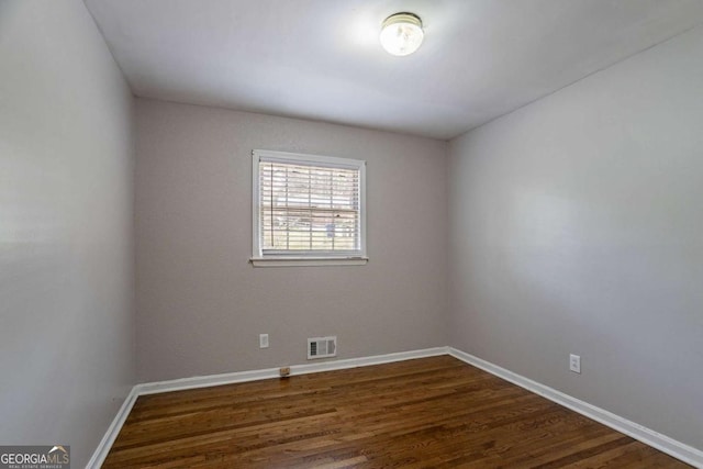unfurnished room with baseboards, dark wood finished floors, and visible vents