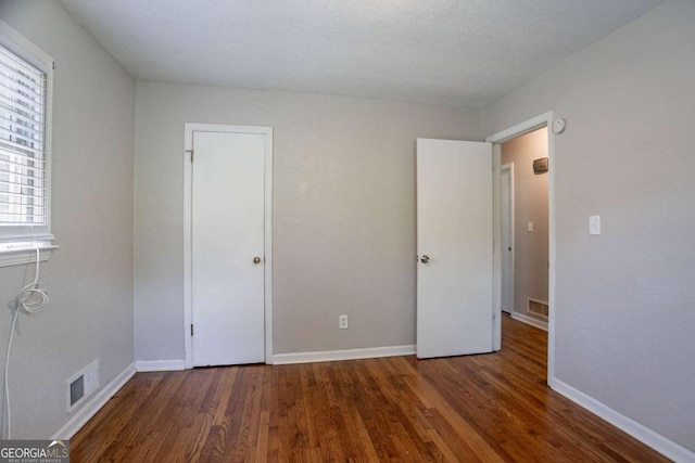 unfurnished bedroom featuring visible vents, baseboards, and wood finished floors