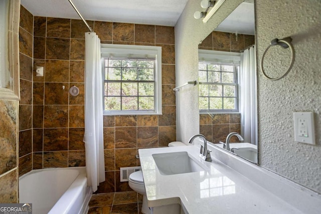 bathroom with visible vents, toilet, tile walls, shower / bathtub combination with curtain, and vanity