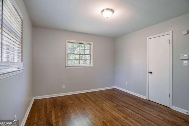unfurnished room with dark wood-type flooring and baseboards