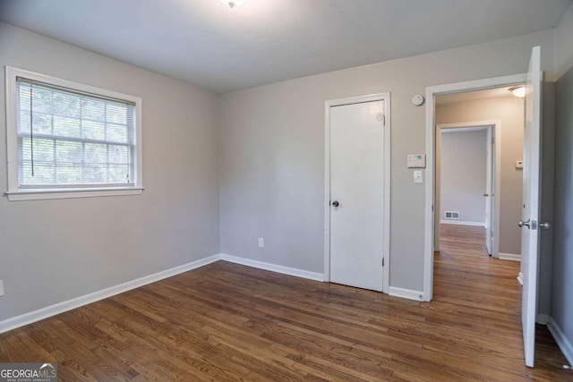 unfurnished bedroom featuring dark wood-style floors, baseboards, and visible vents