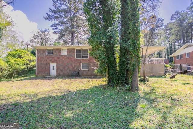 rear view of house with cooling unit, a yard, fence, and brick siding