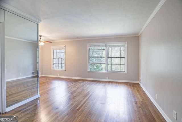 empty room featuring crown molding, baseboards, and wood finished floors