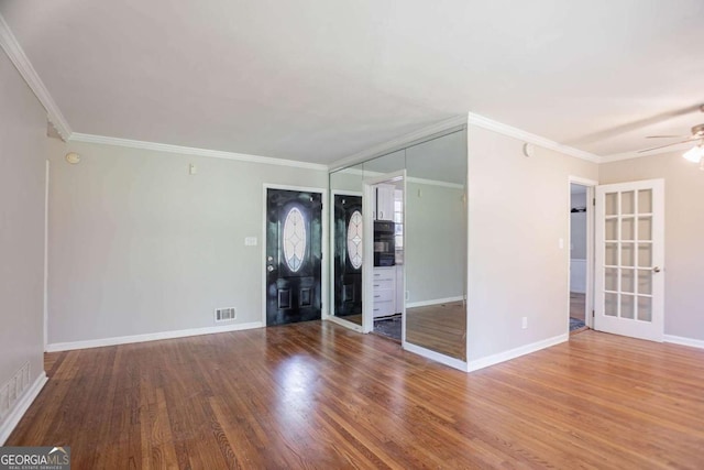 spare room featuring visible vents, ceiling fan, ornamental molding, and wood finished floors