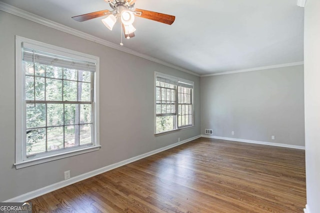 unfurnished room with visible vents, baseboards, crown molding, and wood finished floors