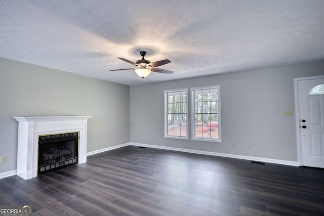 unfurnished living room with ceiling fan, a fireplace, visible vents, dark wood-style flooring, and baseboards