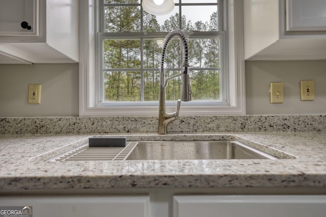 room details featuring a sink and light stone counters