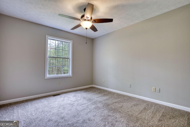 carpeted spare room with visible vents, ceiling fan, baseboards, and a textured ceiling