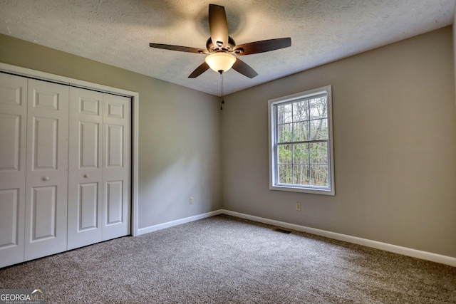unfurnished bedroom featuring baseboards, a closet, carpet flooring, a textured ceiling, and visible vents