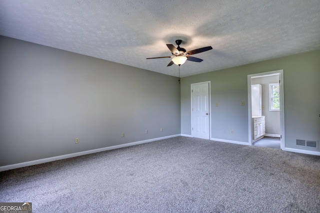 unfurnished bedroom featuring visible vents, baseboards, a textured ceiling, carpet floors, and ensuite bath