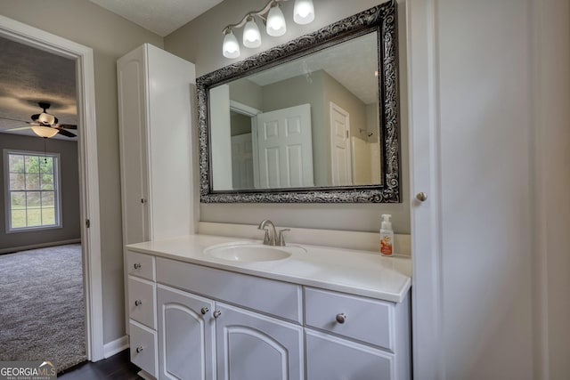 bathroom with a textured ceiling, ceiling fan, baseboards, and vanity