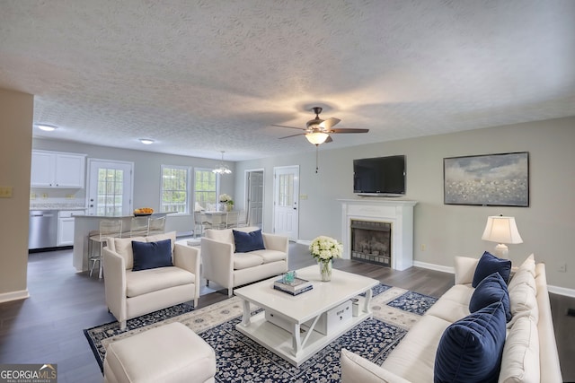 living area featuring dark wood-style floors, baseboards, a textured ceiling, and ceiling fan