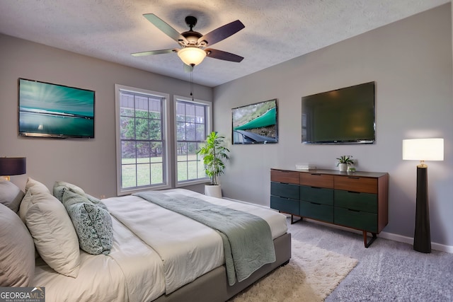 bedroom with ceiling fan, a textured ceiling, light colored carpet, and baseboards