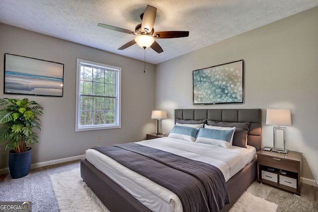 carpeted bedroom featuring baseboards, ceiling fan, and a textured ceiling