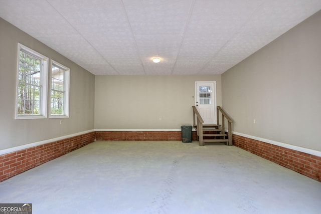 interior space with brick wall, concrete floors, stairway, and a healthy amount of sunlight