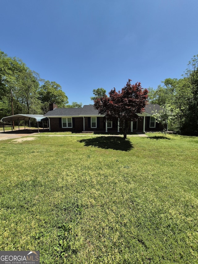 view of front facade with a carport, a chimney, and a front yard