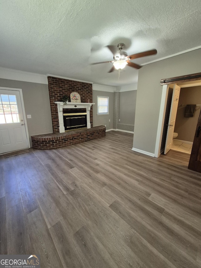 unfurnished living room featuring a textured ceiling, a ceiling fan, ornamental molding, and wood finished floors
