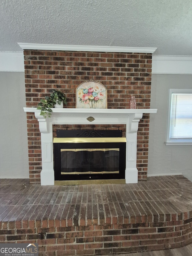 room details with a textured ceiling, ornamental molding, and a brick fireplace