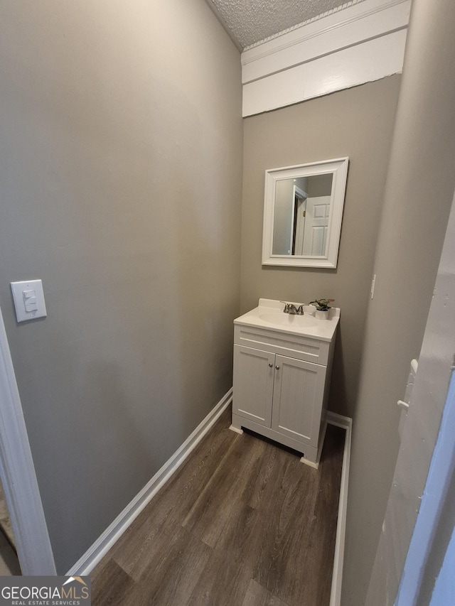 bathroom featuring baseboards, vanity, wood finished floors, and a textured ceiling