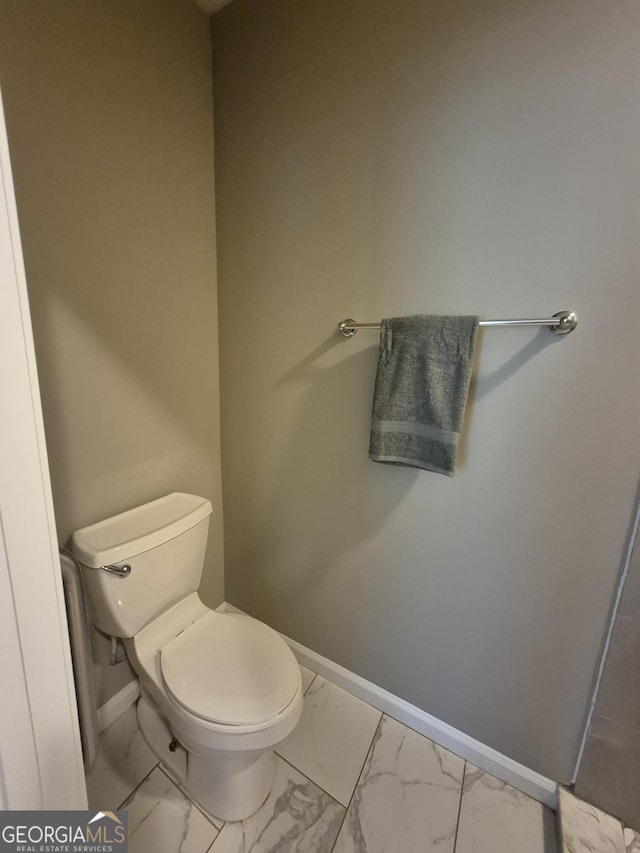 bathroom featuring toilet, baseboards, and marble finish floor
