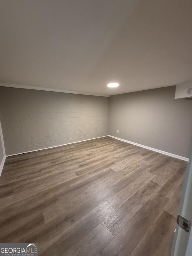 finished below grade area featuring dark wood-style flooring, baseboards, and concrete block wall