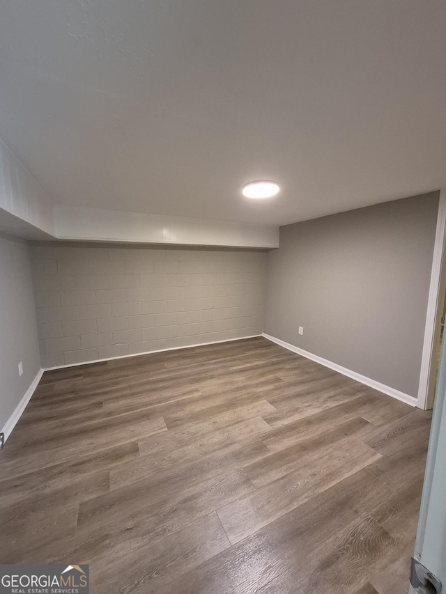 finished below grade area featuring wood finished floors, baseboards, and concrete block wall