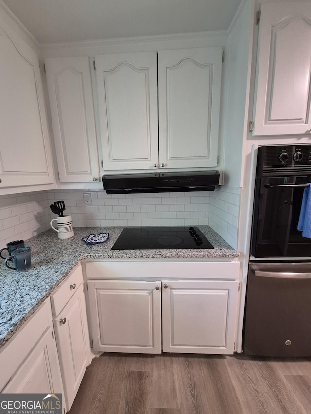 kitchen with tasteful backsplash, white cabinets, black appliances, and under cabinet range hood